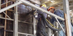 hombres con cascos en su cabeza trabajando sobre andamios